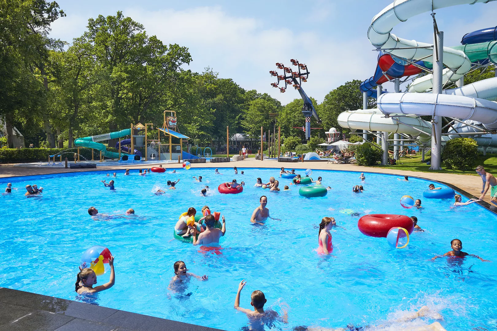 Buitenzwembad met kinderen, attractie en glijbanen op de achtergrond
